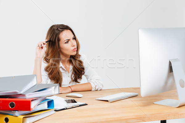 Businesswoman thinking about something and scratching her head with pen Stock photo © deandrobot