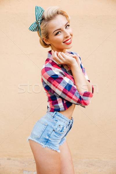 Cheerful cute pinup girl in plaid shirt standing and smiling Stock photo © deandrobot