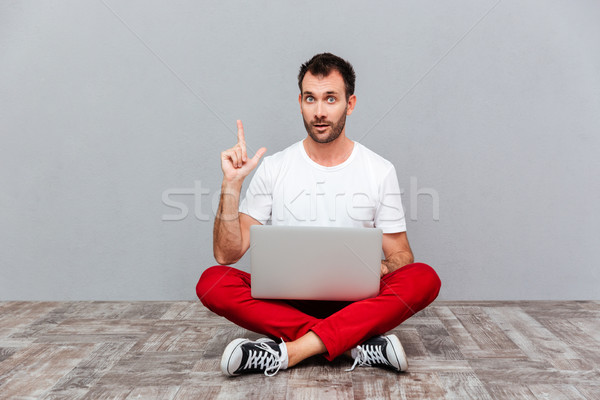 Hombre sesión piso portátil senalando dedo Foto stock © deandrobot