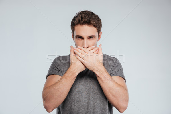 Portré férfi befogja száját mindkettő kezek fiatalember Stock fotó © deandrobot