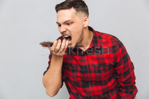 Annoyed casual man in plaid shirt screaming at mobile phone Stock photo © deandrobot