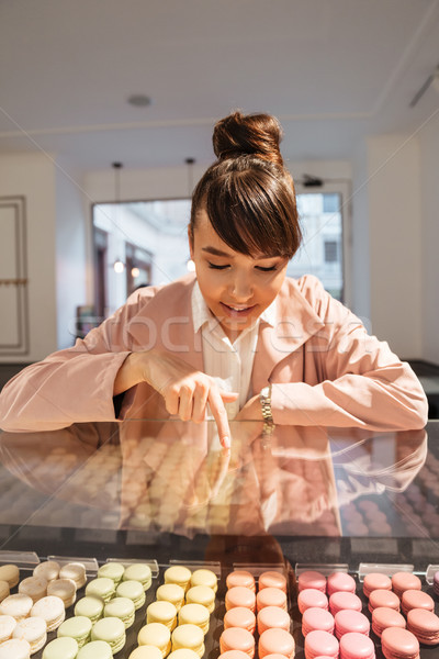 Happy smiling girl looking at pastries through glass showcase Stock photo © deandrobot