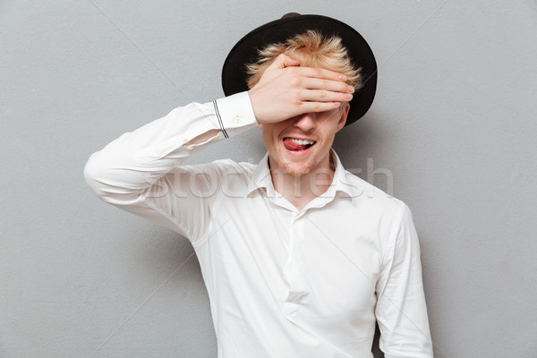Cheerful young caucasian man covering eyes with hand Stock photo © deandrobot