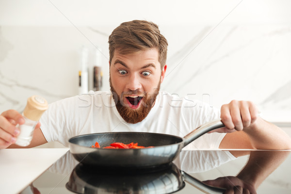 Happy shocked bearded man sprinkle with salt of vegetables Stock photo © deandrobot