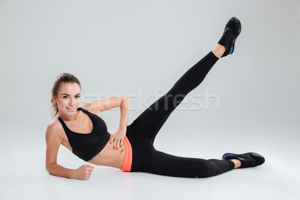 Smiling fitness woman lying and warming up Stock photo © deandrobot