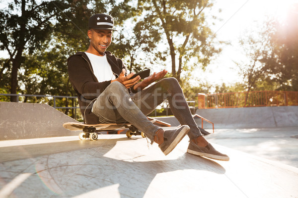 Portrait of a cheerful afro american guy skateboarder playing Stock photo © deandrobot