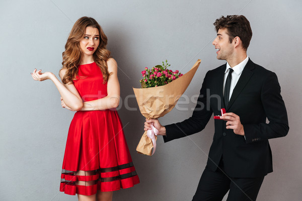 Portrait of a happy man proposing to a unsatisfied girl Stock photo © deandrobot