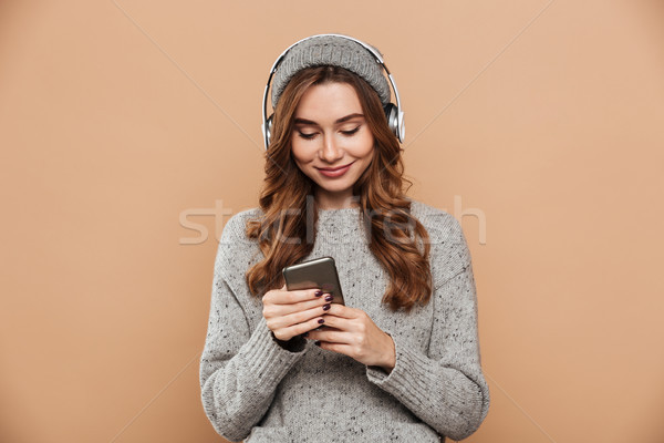 Portrait of young attractive woman in gray hat and sweater using Stock photo © deandrobot