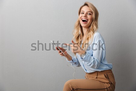 Portrait of a joyful pretty girl pointing finger away Stock photo © deandrobot