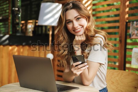 Portré mosolyog töprengő lány tart mobiltelefon Stock fotó © deandrobot