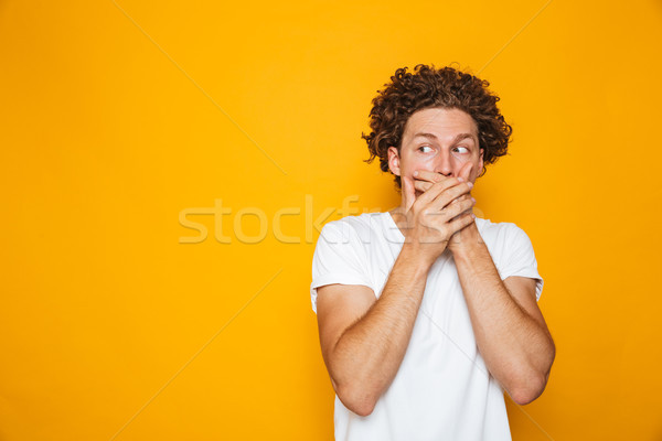 Portrait of a shocked curly haired man covering mouth Stock photo © deandrobot