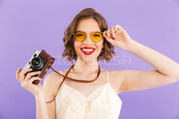 Woman photographer posing isolated over purple wall background holding camera. Stock photo © deandrobot