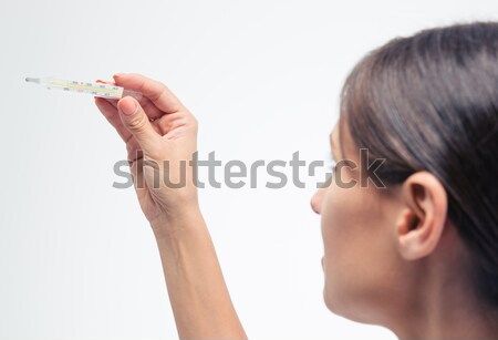 Mujer mirando clínico termómetro aislado blanco Foto stock © deandrobot