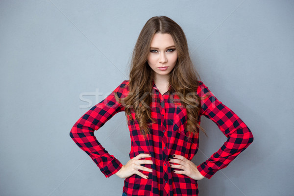 Angry young woman standing with arms akimbo Stock photo © deandrobot
