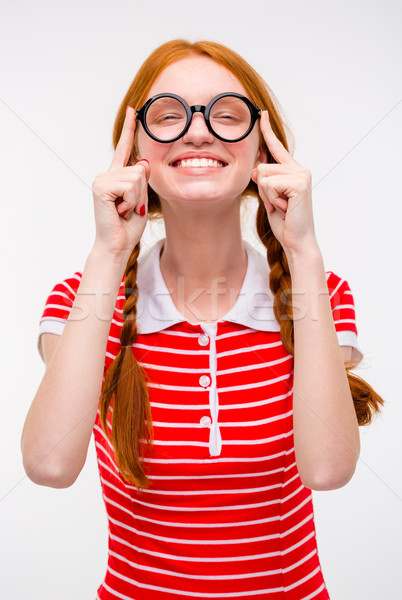 Cheerful funny young female fixing glasses and smiling  Stock photo © deandrobot