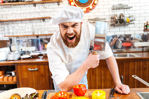Angry bearded chef cook holding meat cleaver knife and shouting  Stock photo © deandrobot