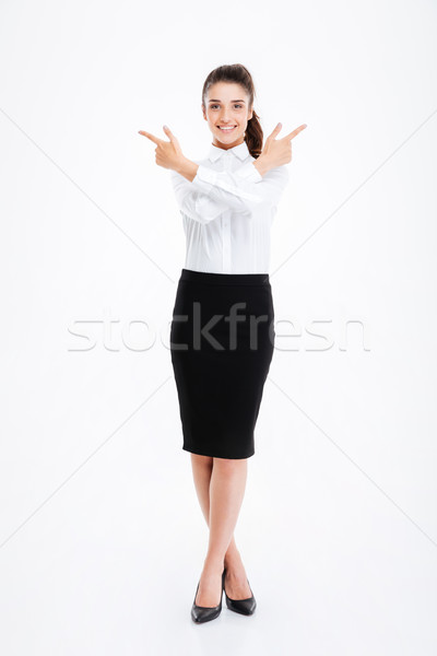 Alegre jóvenes mujer de negocios pie senalando lejos Foto stock © deandrobot