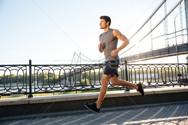 Side view of sportsman running along bridge at sunset light Stock photo © deandrobot