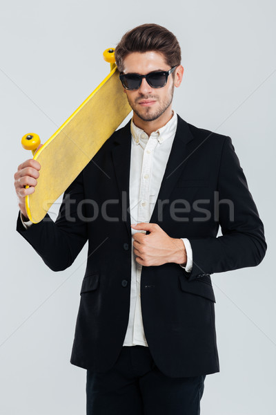 Serious businessman in sunglasses holding yellow skateboard on his shoulder Stock photo © deandrobot