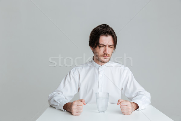 Angry frustrated man sitting at the table with water glass Stock photo © deandrobot