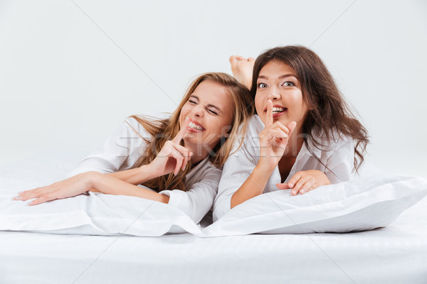 Stock photo: Women lying in bed and showing silence gesture with finger