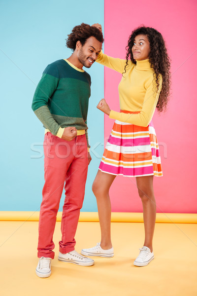 Stock photo: Angry woman pulling hair of her boyfriend and showing fist
