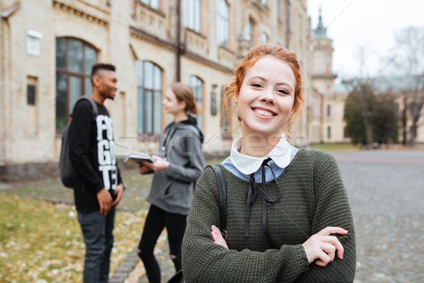 Redhead student standing at the university campus with hands folded Stock photo © deandrobot