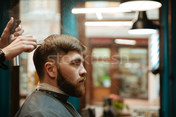 Handsome man getting haircut by hairdresser while sitting in chair. Stock photo © deandrobot