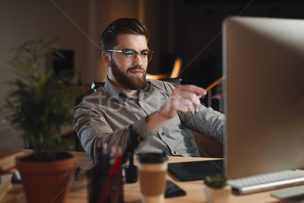Handsome bearded web designer working late at night in office Stock photo © deandrobot
