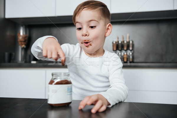 Cute little boy in the kitchen eating sweeties Stock photo © deandrobot