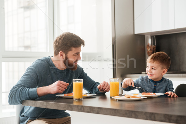 Happy bearded father eating at kitchen with his little son Stock photo © deandrobot
