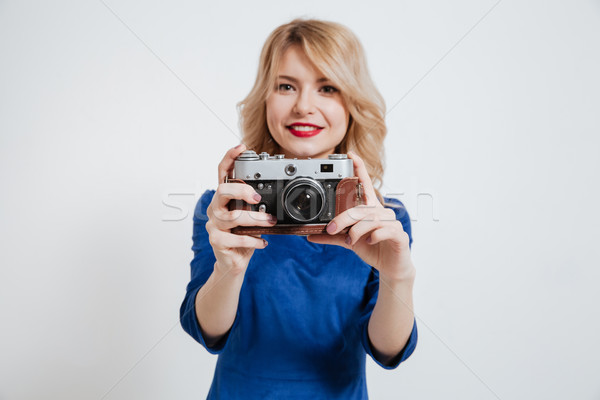 Amazing young lady holding camera over white background. Stock photo © deandrobot