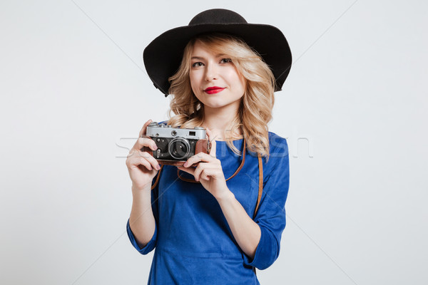Woman dressed in blue dress wearing hat holding camera Stock photo © deandrobot