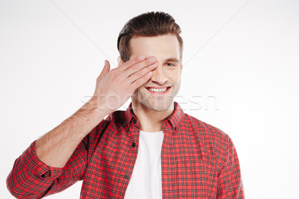 Smiling Man covering one eye Stock photo © deandrobot