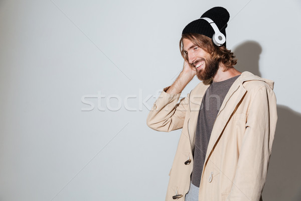 Handsome hipster man looking aside listening music with headphones. Stock photo © deandrobot