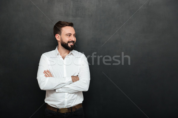 Portrait of positive man in white shirt standing with arms folde Stock photo © deandrobot