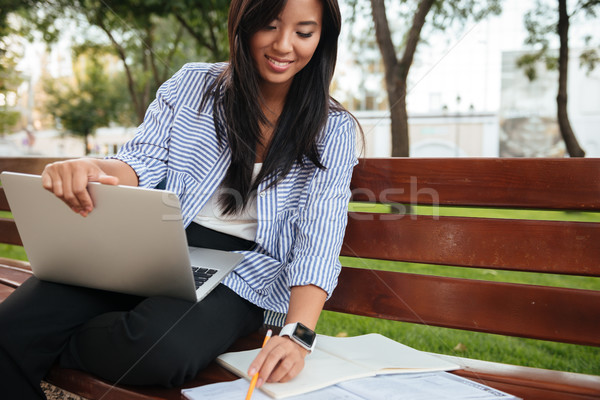 Portrait of cheerful asian student, doing her task in park Stock photo © deandrobot