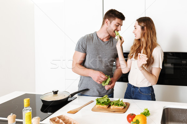 Smiling young couple cooking sandwiches Stock photo © deandrobot