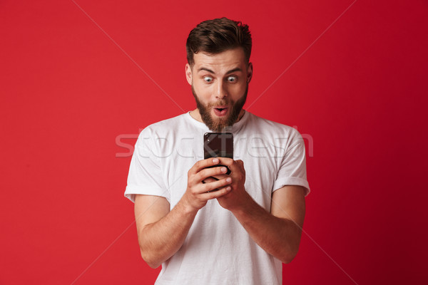 Shocked excited young man using mobile phone. Stock photo © deandrobot