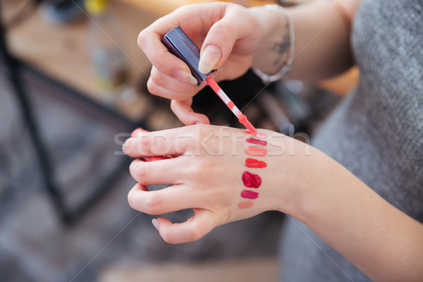 Hands of woman makeup artist testing lip gloss on hand Stock photo © deandrobot