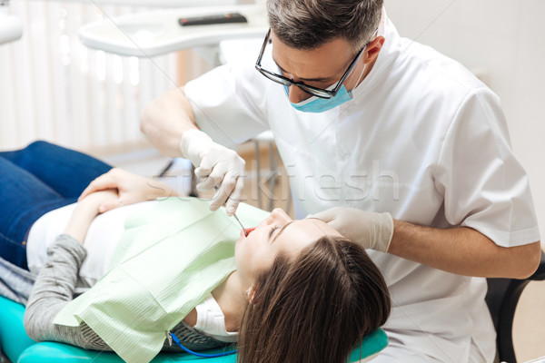Professional dentist doing teeth checkup on female patient dental surgery Stock photo © deandrobot