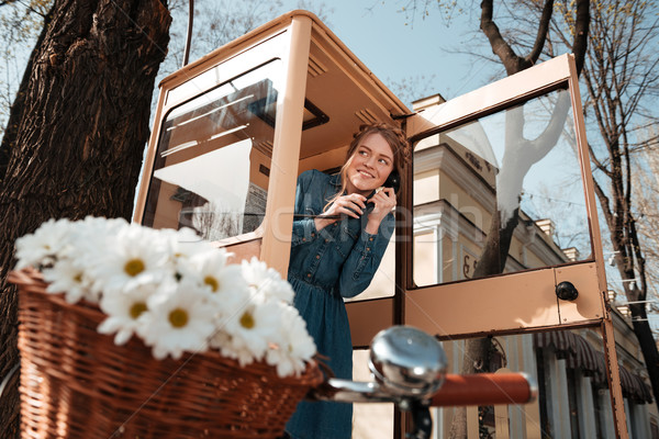 Smiling woman using telephone box on the street Stock photo © deandrobot