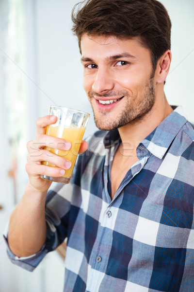 Happy young man in plaid shirt drinking juice at home Stock photo © deandrobot