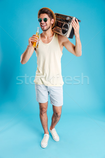 Cheerful young man with boombox walking and drinking beer Stock photo © deandrobot