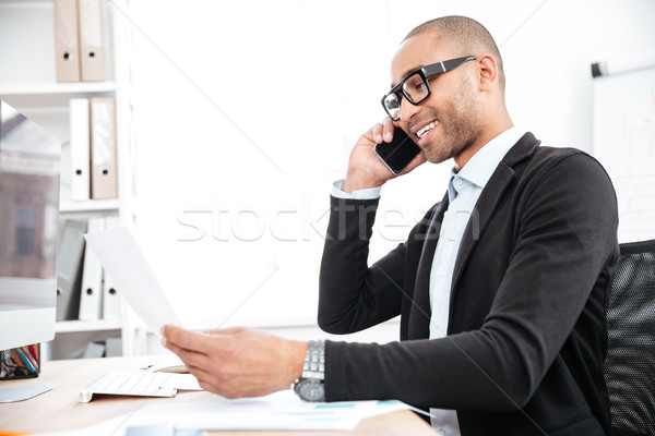 Businessman using mobile phone and looking at documents Stock photo © deandrobot