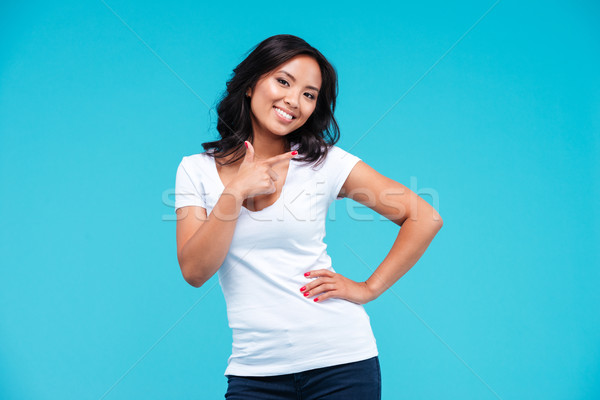 Smiling beautiful young vietnamese girl pointing finger away Stock photo © deandrobot