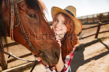 Smiling woman cowgirl standing with her horse on farm Stock photo © deandrobot