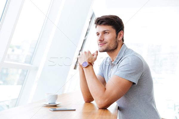 Smiling casual young man having coffee break in cafe Stock photo © deandrobot