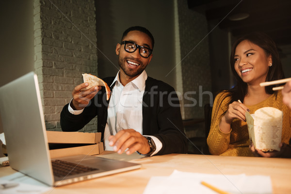 Two colleagues working at night while eating pizza. Stock photo © deandrobot