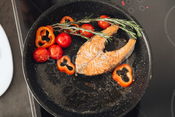 Fish and vegetables on frying pan in kitchen. Stock photo © deandrobot